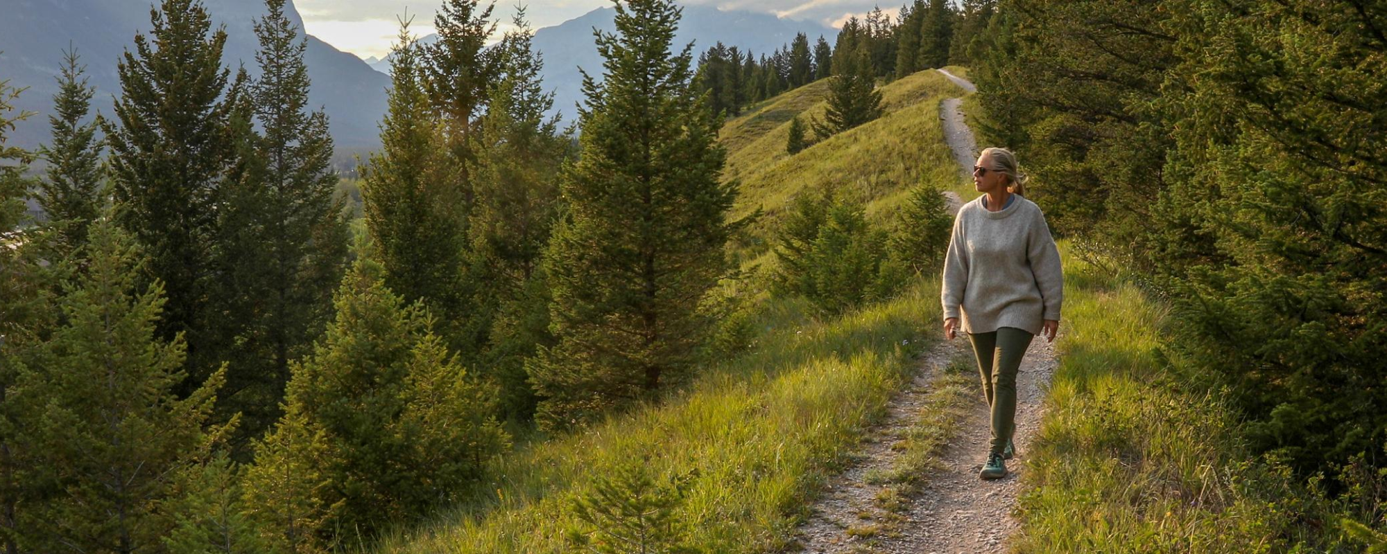 Mature woman walks down trail in the morning.