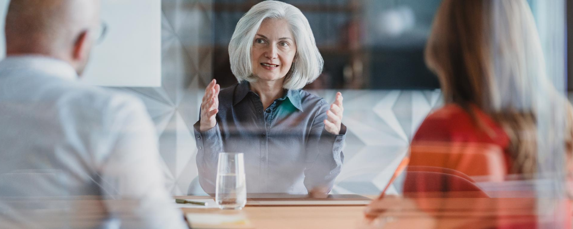 Mature businesswoman talking to colleagues with serious expression.