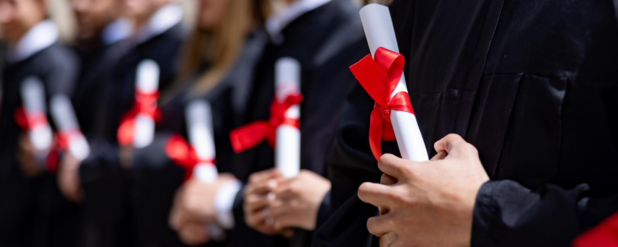 Graduation students holding diploma scrolls.