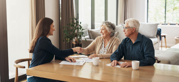 woman in suit shaking hands with elderly couple