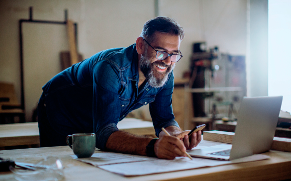 man leaning over desk looking at open laptop