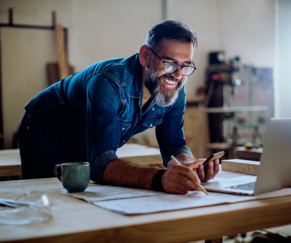 man leaning over desk looking at laptop