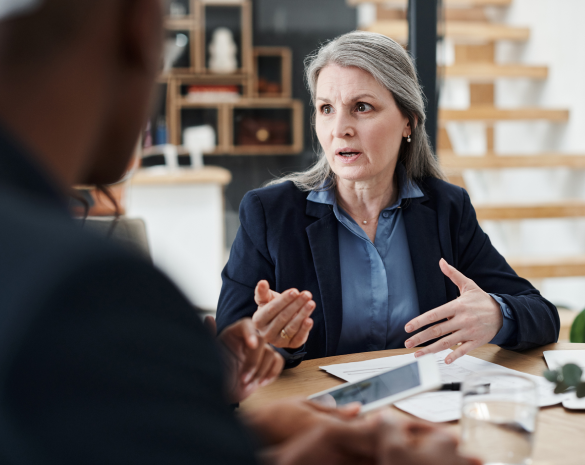 lady is suit sitting at desk with documents
