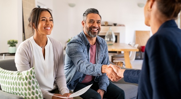 two people sitting at a table shaking another persons hand