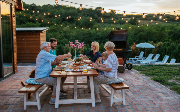 family of six enjoy a meal at a picnic table outside