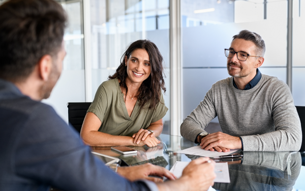 man and woman sit at table speaking to person across from them