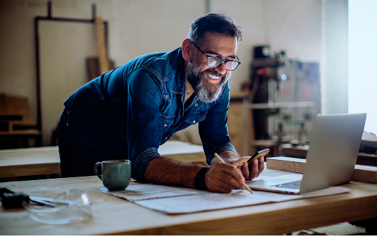 man leaning over desk looking at laptop