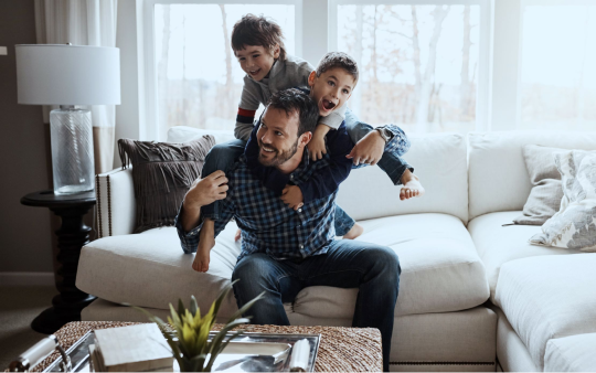 man playing with two boys on a couch