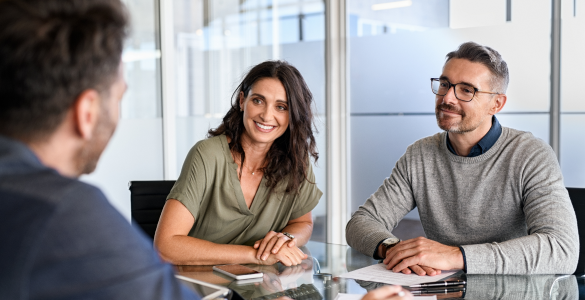 woman and man sitting at desk talking to person in suit