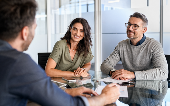 man and woman sit across the table from a man in a suit