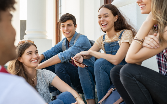 group of young adults sitting outside laughing