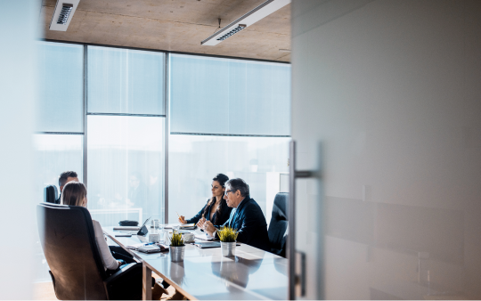 group of 4 people sitting around a table in a board room