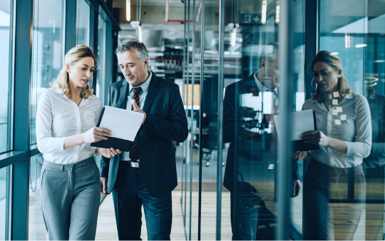 man and woman walking through glass office hallway