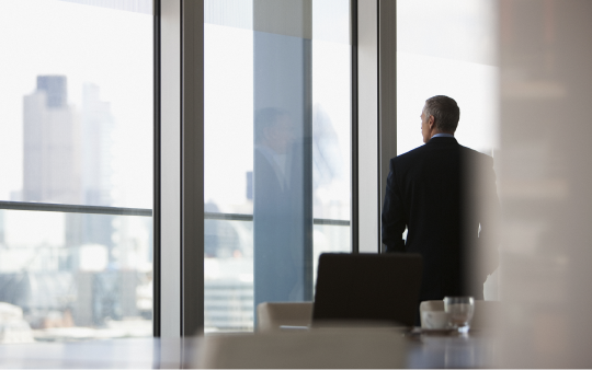 man in suit standing looking out a window