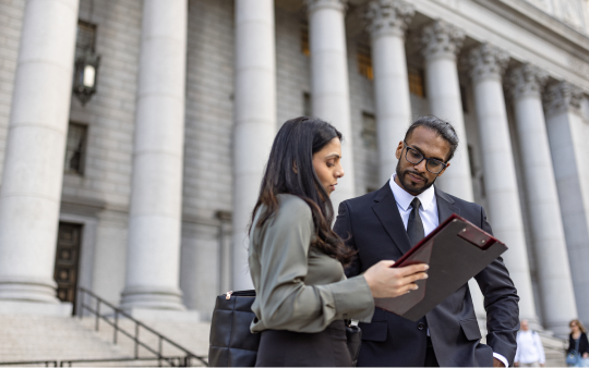 two people stand outside building with doric columns