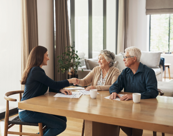 elderly couple shake hands with lady across the table