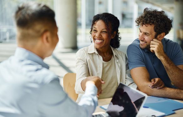 couple shake hands with man sitting across from them