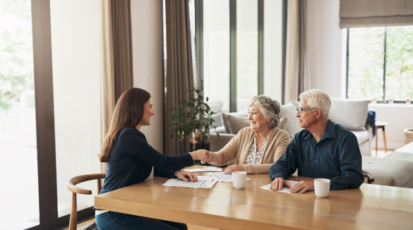 older couple shaking hands with lady sitting across table