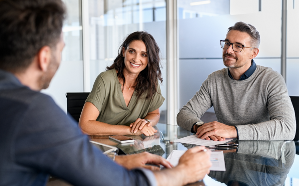 woman and man sitting at desk speaking to man in a suit