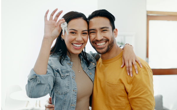 woman and man holding house keys and embracing