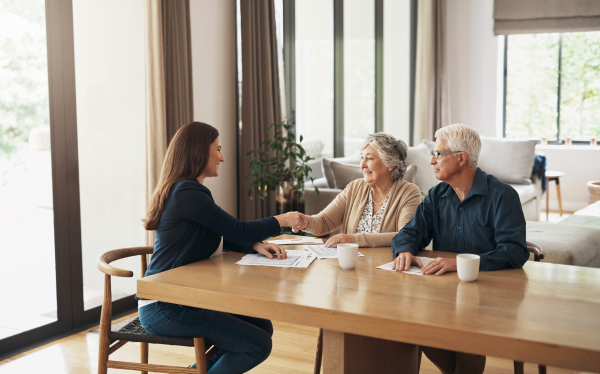 elderly couple sitting at a table talking to a younger lady in a suit