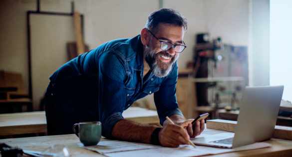 man leaning over table looking at his phone