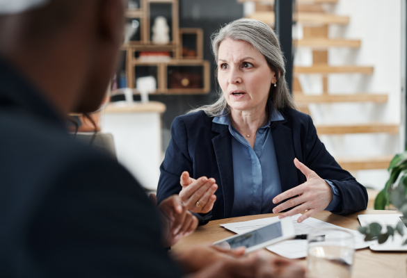 mature woman speaking to people around a table