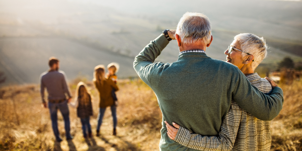 elderly couple hug while watching people in a field